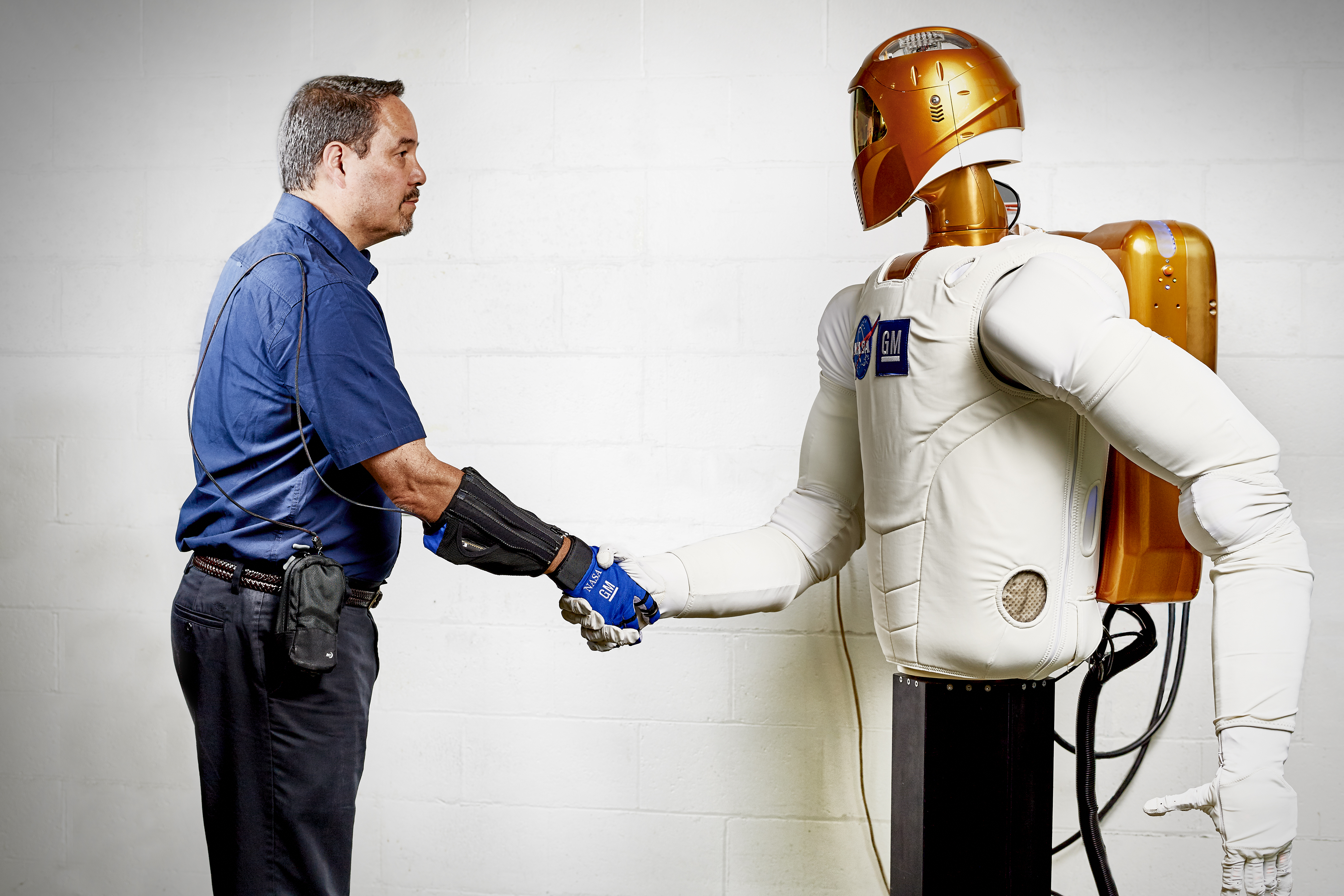Marty Linn, General Motors manager of advanced technology and principal engineer for robotics, shakes hands with Robonaut 2 (R2), a humanoid robot developed by GM and NASA during a nine-year collaboration that also led to development of the RoboGlove, an exo-muscular device that enhances strength and grip through leading-edge sensors, actuators and tendons that are comparable to the nerves, muscles and tendons in a human hand. GM is licensing the RoboGlove intellectual property to Bioservo Technologies AB, a Swedish medical technologies company that will combine RoboGlove with its owner patented SEM glove technology.